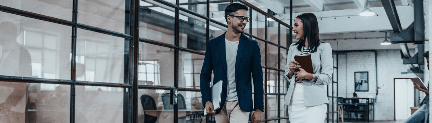 A man in glasses and a jacket holding a laptop